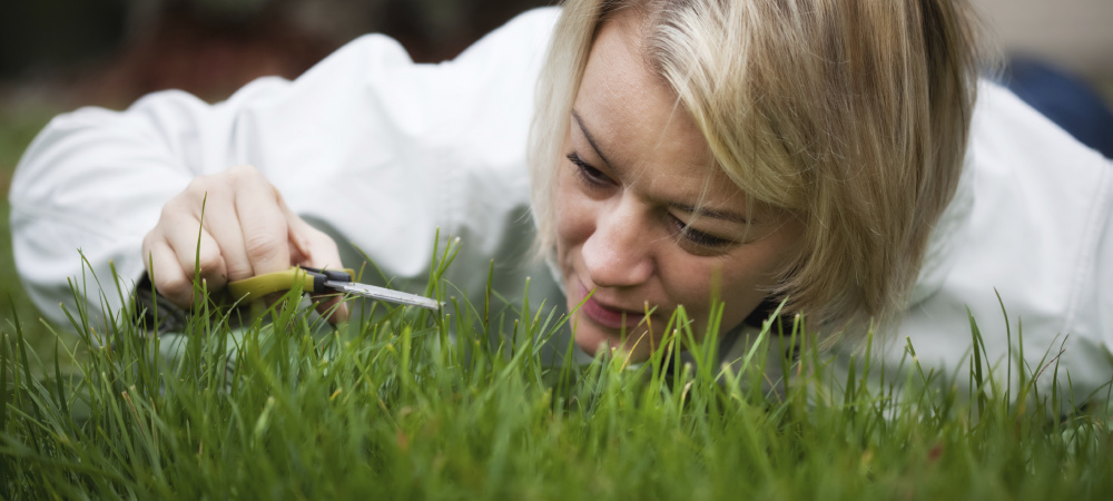 Frau schneidet Rasen mit einer kleinen Schere