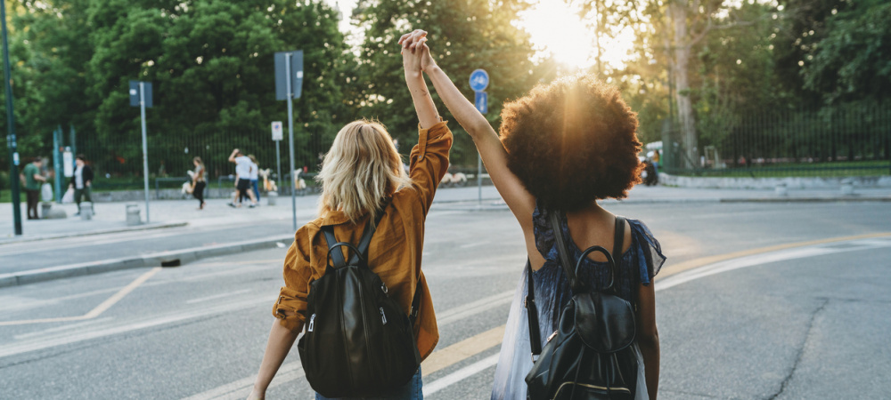 Zwei junge Frauen laufen mit erhobenen Händen durch die Straße