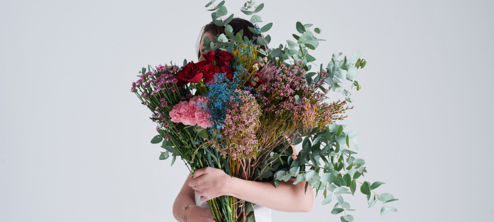Warum Entschuldigen so schwer fällt: Frau mit Blumen vor dem Gesicht