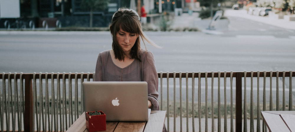 Frau sitzt mit Laptop im Cafe an einer Straße