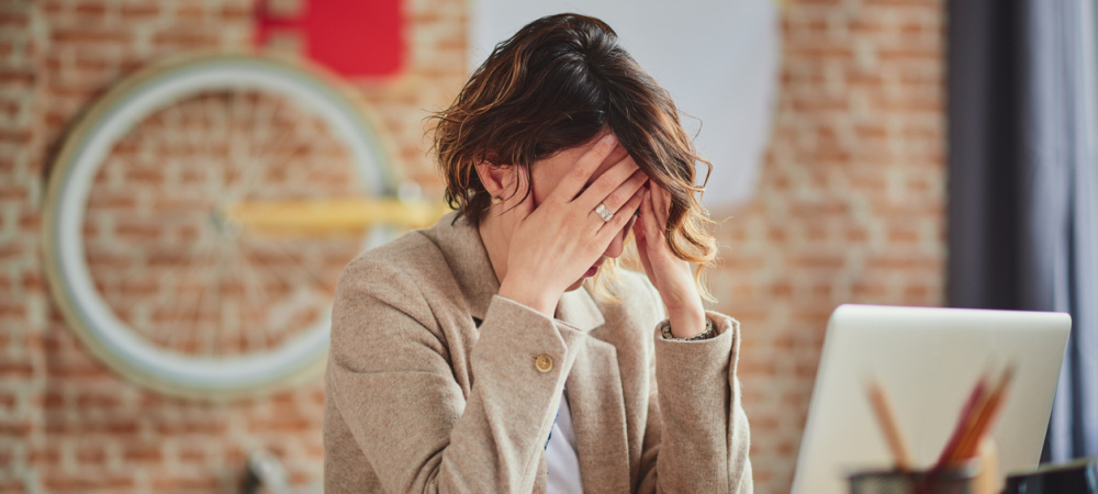 Depressionen im Job: Frau verzweifelt am Schreibtisch