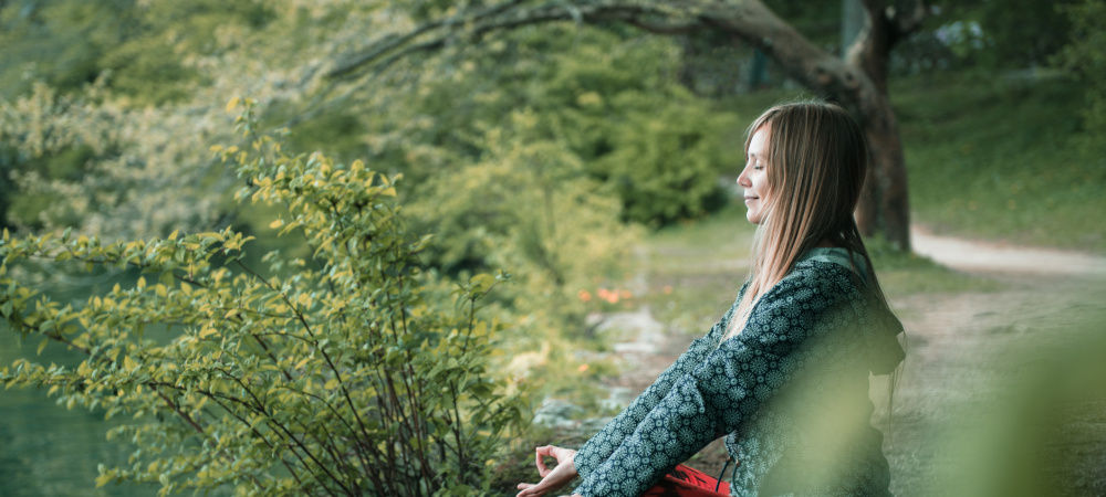 Achtsamkeit im Alltag: Frau meditiert im Wald