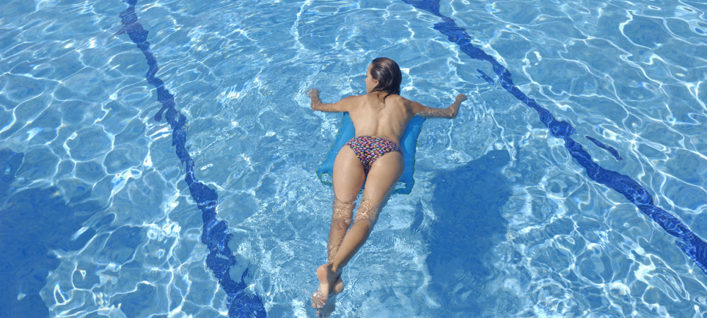 Frau liegt auf einer Luftmatratze im Pool