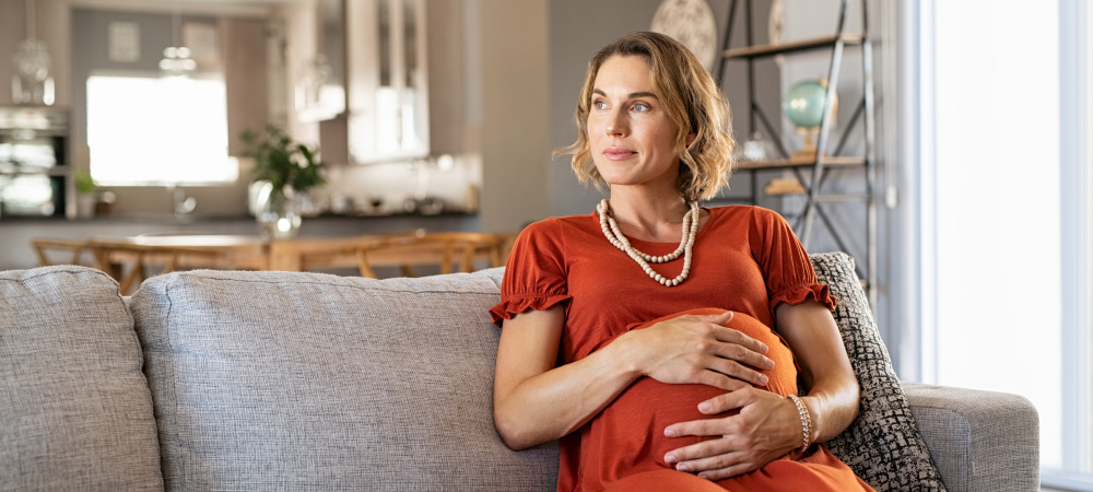 Schwangere Frau sitzt auf dem Sofa Schwanger mit 50