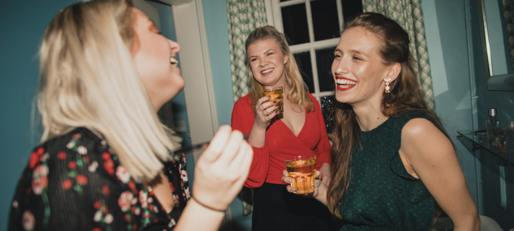 Drei junge Frauen auf einer Hausparty unterhalten sich und lachen
