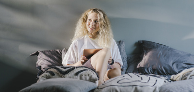 Frau im Bett mit Tablet, 5 Podcasts & Co die dir beim Einschlafen helfen