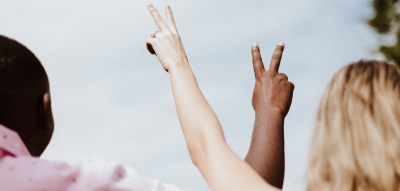 zwei Menschen halten die Hände nach oben und zeigen "Peace"