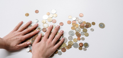 Frau legt ihre Hand auf Euro-Münzen, Gender Pay Gap