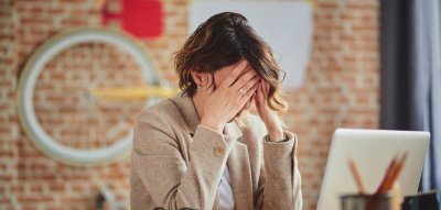 Depressionen im Job: Frau verzweifelt am Schreibtisch