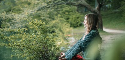 Achtsamkeit im Alltag: Frau meditiert im Wald