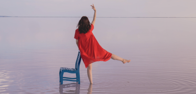Frau steht im Wasser neben einem Stuhl Jahreshoroskop 2023