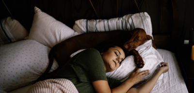 Frau schläft auf der Seite mit Hund im Bett