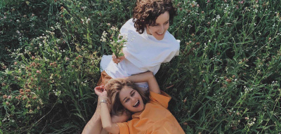 Zwei Frauen liegen auf der Wiese und lachen