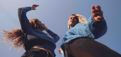 Zwei Frauen tanzen vor dem blauen Himmel, Perspektive von unten 