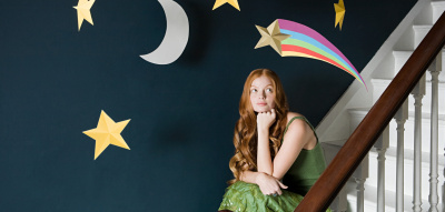 Frau sitzt auf der Treppe unter einem Sternenmobile: Mondzeichen herausfinden