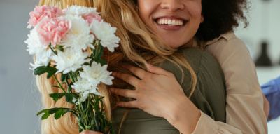 Frauen umarmen sich, haben Blumen in der Hand