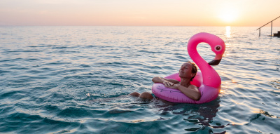 Positive Psychologie: Frau schwimmt mit Flamingo-Luftmatratze