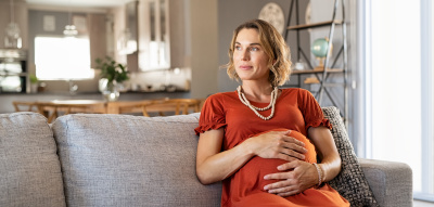 Schwangere Frau sitzt auf dem Sofa Schwanger mit 50