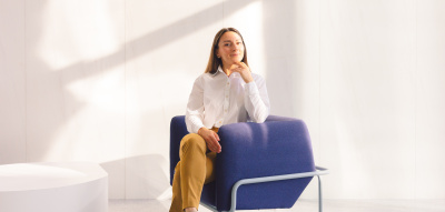 Frau sitzt auf Stuhl, Selbstzweifel im Job loslassen