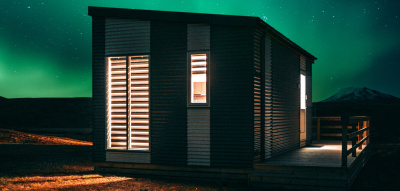 Ein kleines Haus mit beleuchteten Fenstern steht unter dem Sternenhimmel