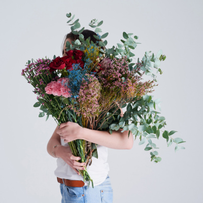 Warum Entschuldigen so schwer fällt: Frau mit Blumen vor dem Gesicht