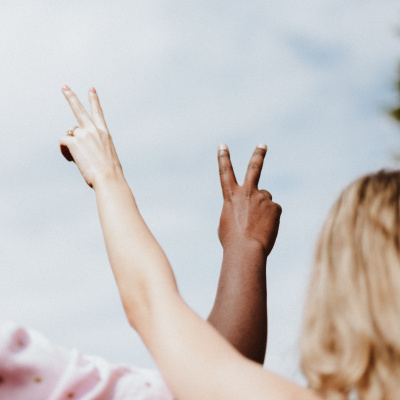 zwei Menschen halten die Hände nach oben und zeigen "Peace"