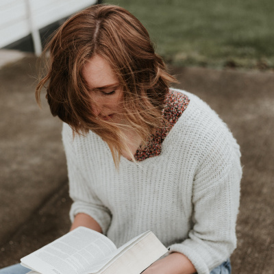 Junge Frau mit weißem Pullover liest ein Buch