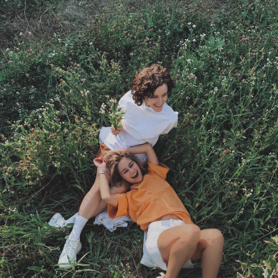 Zwei Frauen liegen auf der Wiese und lachen