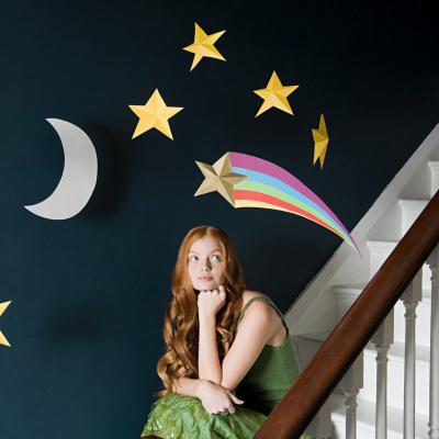 Frau sitzt auf der Treppe unter einem Sternenmobile: Mondzeichen herausfinden