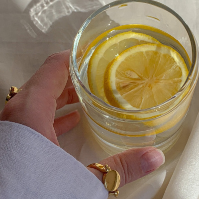 Hand mit Wasserglas und Zitronen