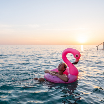 Positive Psychologie: Frau schwimmt mit Flamingo-Luftmatratze