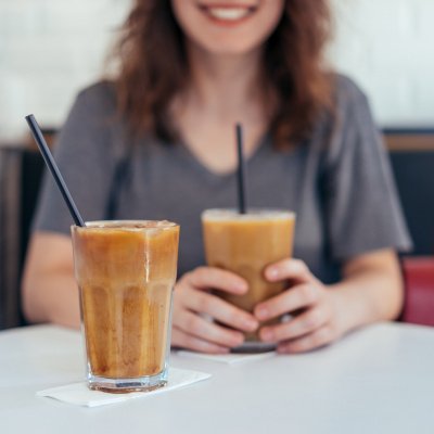 Frau sitzt am Tisch mit zwei Eiskaffee