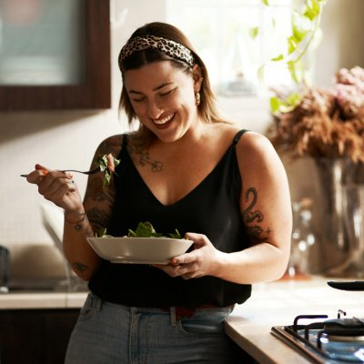 Frau isst Salat in der Küche