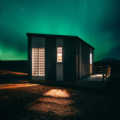 Ein kleines Haus mit beleuchteten Fenstern steht unter dem Sternenhimmel